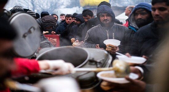 In this Wednesday, Nov. 20, 2019, photograph migrants wait in line for a warm meal at the Vucjak refugee camp outside Bihac, northwestern Bosnia. Despite the approach of harsh weather, hundreds of refugees and migrants are still stuck in northwest Bosnia in a makeshift camp described by international organizations as dangerous and inhumane. (AP Photo/Kemal Softic)