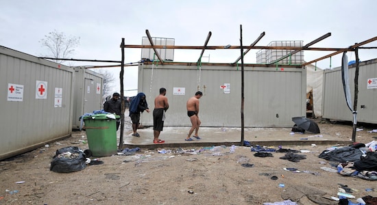 In this Wednesday, Nov. 20, 2019, photograph, migrants shower outdoors at the Vucjak refugee camp outside Bihac, northwestern Bosnia. Despite the approach of harsh weather, hundreds of refugees and migrants are still stuck in northwest Bosnia in a makeshift camp described by international organizations as dangerous and inhumane. Desperate men, including many who have made several unsuccessful attempts to cross into neighboring European Union member Croatia, sleep in the ill-equipped Vucjak tent camp. It is located on a former landfill, not far from a minefield left over from Bosnia's 1992-95 war. (AP Photo/Kemal Softic)