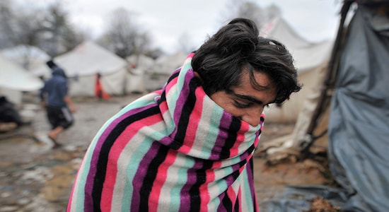 In this Wednesday, Nov. 20, 2019, photograph, a migrant walks covered in a blanket at the Vucjak refugee camp outside Bihac, northwestern Bosnia. Despite the approach of harsh weather, hundreds of refugees and migrants are still stuck in northwest Bosnia in a makeshift camp described by international organizations as dangerous and inhumane. (AP Photo/Kemal Softic)
