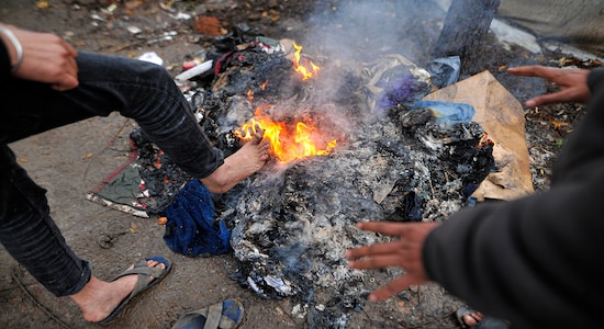 In this Wednesday, Nov. 20, 2019, photograph, migrants warm up next to a fire at the Vucjak refugee camp outside Bihac, northwestern Bosnia. Despite the approach of harsh weather, hundreds of refugees and migrants are still stuck in northwest Bosnia in a makeshift camp described by international organizations as dangerous and inhumane. (AP Photo/Kemal Softic)