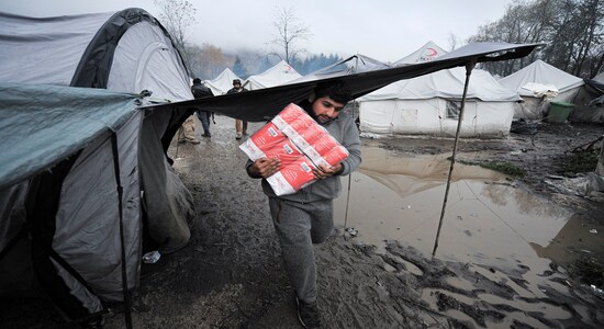 In this Wednesday, Nov. 20, 2019, photograph, a migrant carries supplies at the Vucjak refugee camp outside Bihac, northwestern Bosnia. (AP Photo/Kemal Softic)