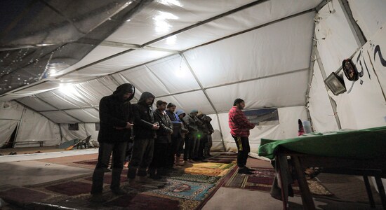 In this Wednesday, Nov. 20, 2019, photograph, migrants pray in a tent at the Vucjak refugee camp outside Bihac, northwestern Bosnia. (AP Photo/Kemal Softic)