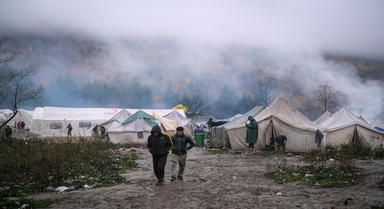 In this Wednesday, Nov. 20, 2019, photograph, migrants walk at the Vucjak refugee camp outside Bihac, northwestern Bosnia. Hundreds of refugees and migrants remain stuck in northwest Bosnia in a makeshift camp described by numerous international organizations as dangerous and inhuman, where desperate men, including many who have made several unsuccessful attempts to cross into neighboring European Union member Croatia, sleep in a tent camp located on a former landfill, not far from a mine field left over from Bosnia's 1992-95 war.(AP Photo/Kemal Softic)