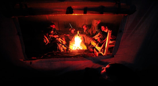 In this Wednesday, Nov. 20, 2019, photograph, migrants sit around a fire at the Vucjak refugee camp outside Bihac, northwestern Bosnia. Hundreds of refugees and migrants remain stuck in northwest Bosnia in a makeshift camp described by numerous international organizations as dangerous and inhuman, where desperate men, including many who have made several unsuccessful attempts to cross into neighboring European Union member Croatia, sleep in a tent camp located on a former landfill, not far from a mine field left over from Bosnia's 1992-95 war.(AP Photo/Kemal Softic)