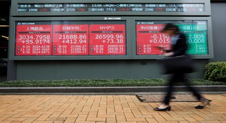 A woman walks past an electric screen showing world markets indices outside a brokerage in Tokyo, Japan, July 1, 2019. REUTERS/Issei Kato
