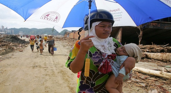 FILE PHOTO: An Indonesian woman carries her child in Lhoknga district, southwest of Banda Aceh, as they head towards the provincial capital to seek food and shelter following the deadly tsunami, on the Indonesian island of Sumatra January 1, 2005. REUTERS/Beawiharta