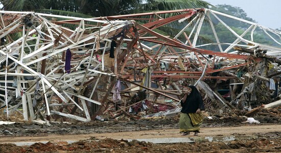 FILE PHOTO: A Sri Lankan woman walks past a destroyed electrical pylon in Hambantota, eastern Sri Lanka, January 8, 2005 which collapsed after a tsunami hit the country's coast on December 26, 2004. REUTERS/Yves Herman