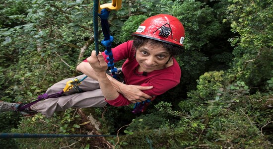 In this 2014 photo provided by Sybil Gotsch shows ecologist Nalini Nadkarni studying the rainforest canopy in the Monteverde region of Costa Rica. Nadkarni's childhood climbing trees shaped her career and now she's hoping she can get help kids interested in science in an new way: Barbies. Nadkarni has long created her own &quot;treetop Barbies&quot; and has now helped Mattel and National Geographic create a line of dolls with careers in science and conservation. (Sybil Gotsch, via AP)