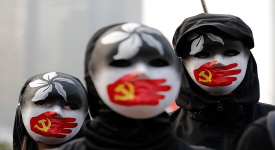In this Sunday, Dec. 22, 2019, file photo, people wearing masks stand during a rally to show support for Uighurs and their fight for human rights in Hong Kong. (AP Photo/Lee Jin-man, File)