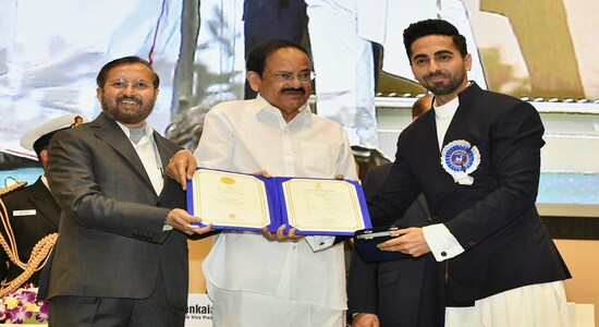 Vice President Venkaiah Naidu, center, presents the national film award to Bollywood actor Ayushmann Khurrana, right, who shared the best actor award with actor Vicky Kaushal during the national film awards ceremony in New Delhi, India, Monday, Dec.23, 2019. Information and Broadcasting Minister Prakash Javdekar is on left. (AP Photo)