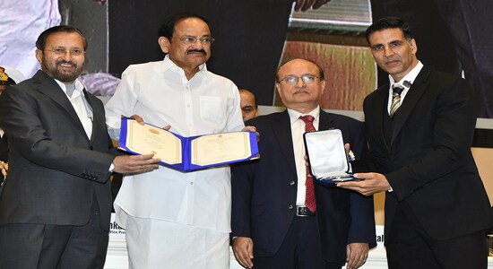 Vice President Venkaiah Naidu, second left, presents the award for best film on social issues to Padman, being received by Bollywood actor Akshay Kumar, right, during the national film awards ceremony in New Delhi, India, Monday, Dec.23, 2019. Information and Broadcasting Minister Prakash Javdekar is on left. (AP Photo)