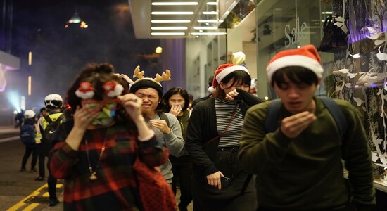 Residents dressed for Christmas festivities react to tear gas as police confront protesters on Christmas Eve in Hong Kong on Tuesday, Dec. 24, 2019. More than six months of protests have beset the city with frequent confrontations between protesters and police. (AP Photo/Kin Cheung)