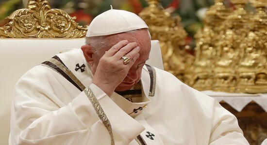 Pope Francis touches his forehead as he celebrates Christmas Eve Mass in St. Peter's Basilica at the Vatican, Tuesday, Dec. 24, 2019. The evening Mass kicks off a busy few days for the pope, commemorating the birth of Christ and the start of a new year. (AP Photo/Alessandra Tarantino)