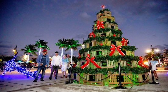In this Monday, Dec. 23, 2019, photo provided by the Florida Keys News Bureau, people examine a Christmas tree fabricated from lobster traps along the Harbor Walk of Lights at the Key West Historic Seaport in Key West, Fla. The showcase is among many island-wide attractions during Key West Holiday Fest, that continues through New Year's Eve. (Carol Tedesco/Florida Keys News Bureau via AP)