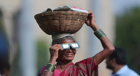In this Thursday, Dec. 26, 2019, file photo, a roadside vendor holds a special filter and watches a partial solar eclipse in Hyderabad, India, Thursday, Dec. 26, 2019. (AP Photo/Mahesh Kumar A., File)