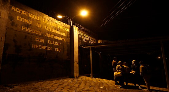 Family members wait outside the prison gate for news from their imprisoned relatives, outside the Tela prison where at least 18 inmates were killed on Friday, in Tela, Honduras, early Saturday, Dec. 21, 2019. The violence came several days after Honduras declared a state of emergency in its prison system. (AP Photo/Delmer Martinez)
