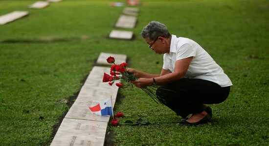 A woman places flowers on the grave of a person who died during the 1989 U.S. military invasion that ousted Panamanian strongman Manuel Noriega, on the 30th anniversary of the invasion in Panama City, Friday, Dec. 20, 2019. According to official figures, 300 Panamanian soldiers and 214 civilians died during the invasion, though the number remains controversial and human rights groups believe it is much higher. Twenty-three U.S. soldiers also perished. (AP Photo/Arnulfo Franco)