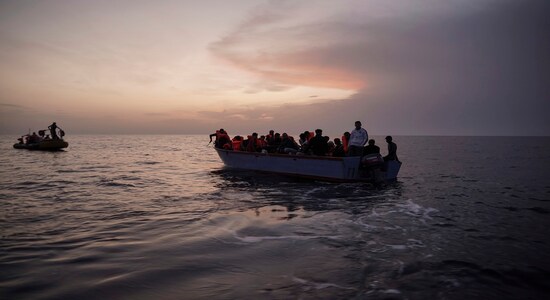 In this Sept. 19, 2019 photo, migrants on an overcrowded wooden boat wait to be rescued by the Ocean Viking humanitarian ship in the Mediterranean Sea. The misery of migrants in Libya has spawned a thriving and highly lucrative business, in part funded by the EU and enabled by the United Nations, an Associated Press investigation has found. (AP Photo/Renata Brito)