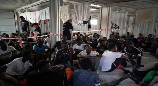 In this Sept. 18, 2019 photo, migrants rescued at sea rest in the men's shelter aboard the Ocean Viking humanitarian ship as it sails in the Mediterranean Sea. The misery of migrants in Libya has spawned a thriving and highly lucrative business, in part funded by the EU and enabled by the United Nations, an Associated Press investigation has found. (AP Photo/Renata Brito)