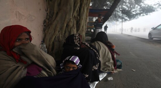 A woman covers her child under a blanket and sits outside a temple with others amidst dense fog early morning in New Delhi, India, Monday, Dec. 30, 2019. Delhi, which is witnessing the longest spell of cold weather in the last 22 years, woke up to a blanket of dense fog engulfing most parts of the national capital on Monday morning, disrupting rail, road and air traffic adversely. (AP Photo/Manish Swarup)