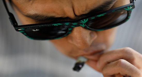 A man wearing pot leaf sunglasses smokes a joint outside the Mexican Senate, during a protest calling for the legalization of marijuana, in Mexico City, Tuesday, Dec. 31, 2019. Cannabis advocates are hoping lawmakers will decriminalize marijuana in 2020. (AP Photo/Rebecca Blackwell)
