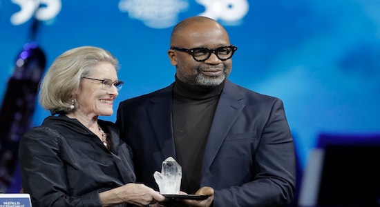 Artist Theaster Gates, from the United States, receives a Crystal Award from Hilde Schwab, Chairwoman and Co-Founder of the World Economic Forum's World Arts Forum, during the ceremony for the Crystal Awards at the annual meeting of the World Economic Forumin Davos, Switzerland, Monday, Jan. 20, 2020. The 50th annual meeting of the forum will take place in Davos from Jan. 21 until Jan. 24, 2020. (AP Photo/Markus Schreiber)