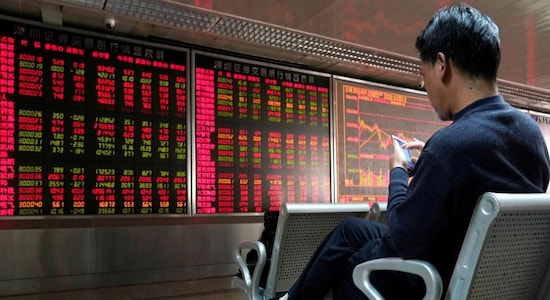 FILE PHOTO: An investor uses his mobile phone in front of a stock quotation board at a brokerage office in Beijing, China January 3, 2020. REUTERS/Jason Lee
