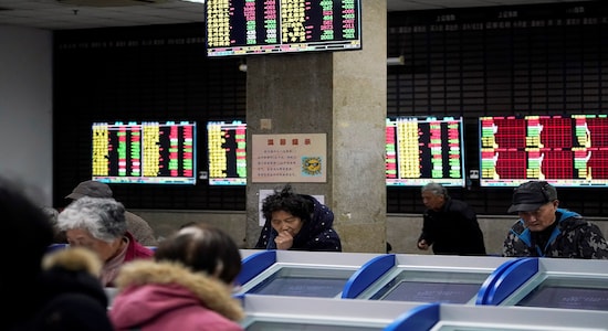 Investors look at computer screens showing stock information at a brokerage house in Shanghai