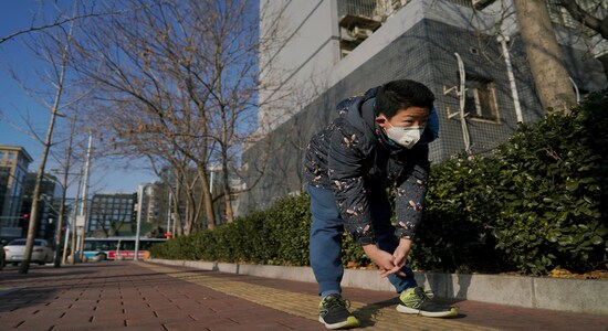 A boy wearing a face mask exercises outside a residential compound, as the country is hit by an outbreak of the novel coronavirus, in Beijing, China February 15, 2020. REUTERS/Stringer