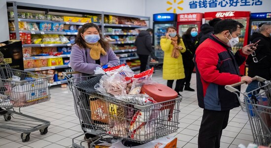 FILE - In this Jan. 22, file 2020 photo, shoppers wear face masks as they line up at a grocery store in Wuhan in central China's Hubei Province. Arek and Jenina Rataj were starting a new life in the Chinese industrial center of Wuhan when a viral outbreak spread across the city of 11 million. While they were relatively safe sheltering at home, Arek felt compelled to go out and document the outbreak of the new type of coronavirus. Among his subjects: the construction of a new hospital built in a handful of days; biosecurity check points; and empty streets. (AP Photo/Arek Rataj, File)