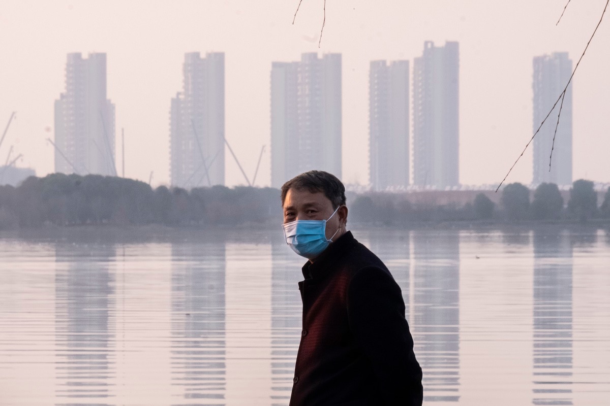 FILE - In this Jan. 30, 2020 file photo, a man wears a face mask as he stands along the waterfront in Wuhan in central China's Hubei Province. Arek and Jenina Rataj were starting a new life in the Chinese industrial center of Wuhan when a viral outbreak spread across the city of 11 million. While they were relatively safe sheltering at home, Arek felt compelled to go out and document the outbreak of the new type of coronavirus. Among his subjects: the construction of a new hospital built in a handful of days; biosecurity check points; and empty streets. (AP Photo/Arek Rataj, File)