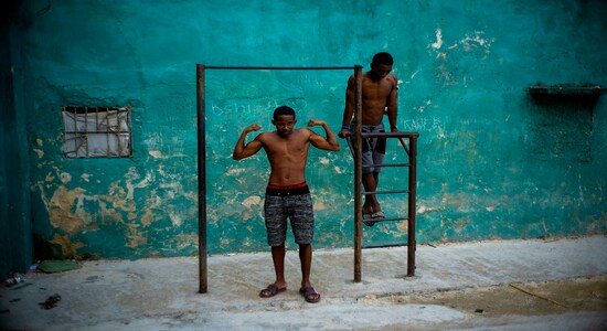 A young man strikes a pose showing off his muscles, framed by a pull up bar in Havana, Cuba, Wednesday, Feb. 5, 2020. (AP Photo/Ramon Espinosa)