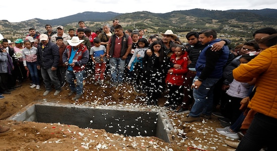 Flower petals fall as family and friends grieve around the grave of community activist Homero Gomez Gonzalez in Ocampo, Michoacan state, Mexico, Friday, Jan. 31, 2020. Hundreds of farmers and agricultural workers thronged the funeral on Friday, and the homage to the anti-logging activist was like a tribute to the monarch butterfly he so staunchly defended. (AP Photo/Rebecca Blackwell)