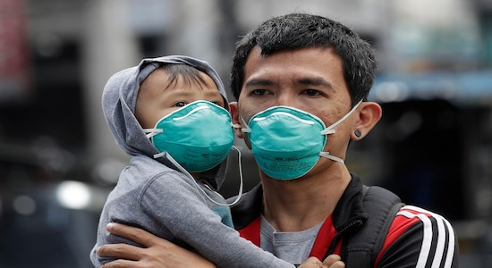 A man and a child wear protective masks in Manila, Philippines, Wednesday Feb. 5, 2020. The Philippines precautionary measures remain tight around the country from the coronavirus. (AP Photo/Aaron Favila)