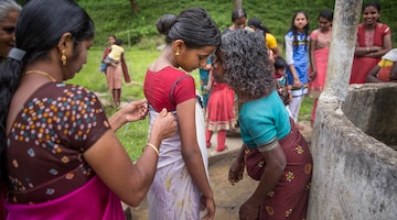 A Panniya woman whispers secrets of womanhood into the ears of 14-year-old Asha during her coming-of-age ceremony.