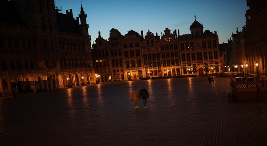 People walk along the virtually empty Grand Place in downtown Brussels, March 18, 2020. (AP Photo/Francisco Seco)