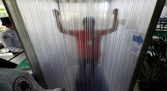 A man is disinfected inside a cubicle before entering local the city hall to prevent the spread of the new coronavirus in Manila, Philippines on Tuesday, March 24, 2020. For most people the new coronavirus causes only mild or moderate symptoms, but for some it can cause more severe illness. (AP Photo/Aaron Favila)