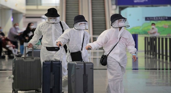 Passengers wear protective suits and face masks as they arrive at the Hong Kong airport, Monday, March 23, 2020. The new coronavirus causes mild or moderate symptoms for most people, but for some, especially older adults and people with existing health problems, it can cause more severe illness or death. (AP Photo/Kin Cheung)