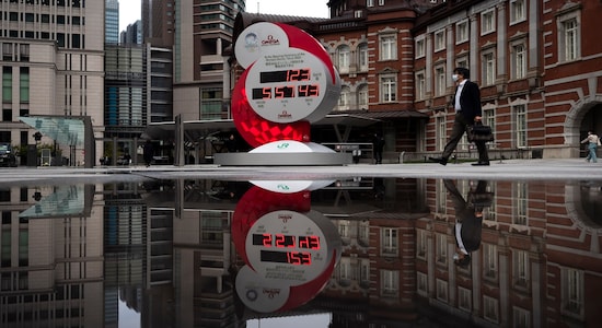 A countdown clock for the Tokyo 2020 Olympics is reflected in a puddle of water outside Tokyo Station in Tokyo, Monday, March 23, 2020. On Tuesday, March 24, Japan and the International Olympic Committee agreed to postpone the Tokyo Olympic Games until the summer of 2021 because of the coronavirus pandemic.(AP Photo/Jae C. Hong)