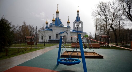 A caution tape cordons off an empty children's playground with an Orthodox church seen in the background, officially closed for parishioners according to the order of the city authorities due to coronavirus, in Moscow, Russia, April 18, 2020. (AP Photo/Alexander Zemlianichenko)