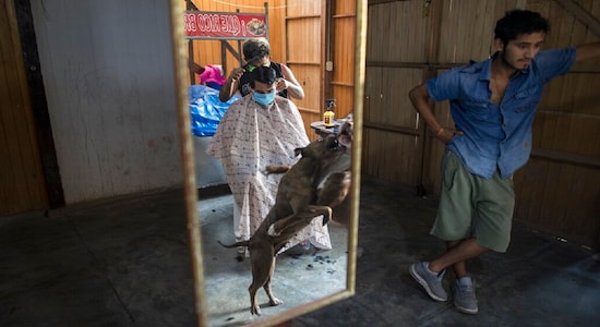 Estefano Godo, 19, cuts the hair of Alexander Placencia, 29, at his house due to the coronavirus emergency, in the outskirts of Lima, Peru, April 22, 2020. &quot;Working inside my house with few clients it's the only way of earning some money to survive in this crisis,&quot; said Godo who's beauty salon has been forced to close. (AP Photo/Rodrigo Abd)