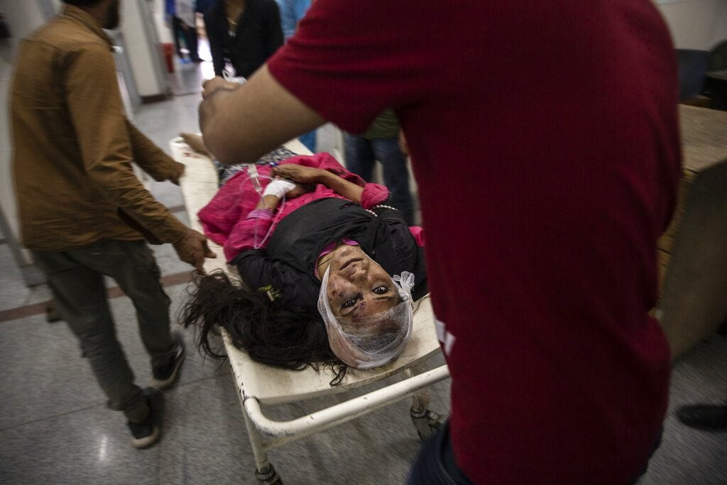 A wounded woman is carried on a stretcher for treatment after she was injured in a bus accident, at a local hospital in Srinagar, June 27, 2019. A minibus carrying students to a picnic fell into a gorge along a Himalayan road in Kashmir, killing more than 10 and injuring several others. (AP Photo/Dar Yasin)