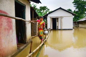 lood-affected people use a banana raft to shift to safe place, in Bajali district of Assam