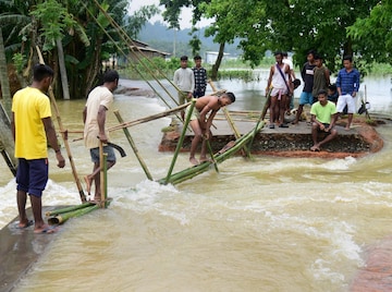 Villagers make a temporary bamboo bridge after a portion of a road was washed away by the flood water at a village in Goalpara district of Assam 