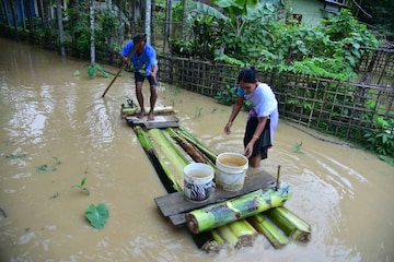  Villagers use a banana raft to cross a flooded street, in Nagaon district of Assam, Sunday, June 19, 2022.