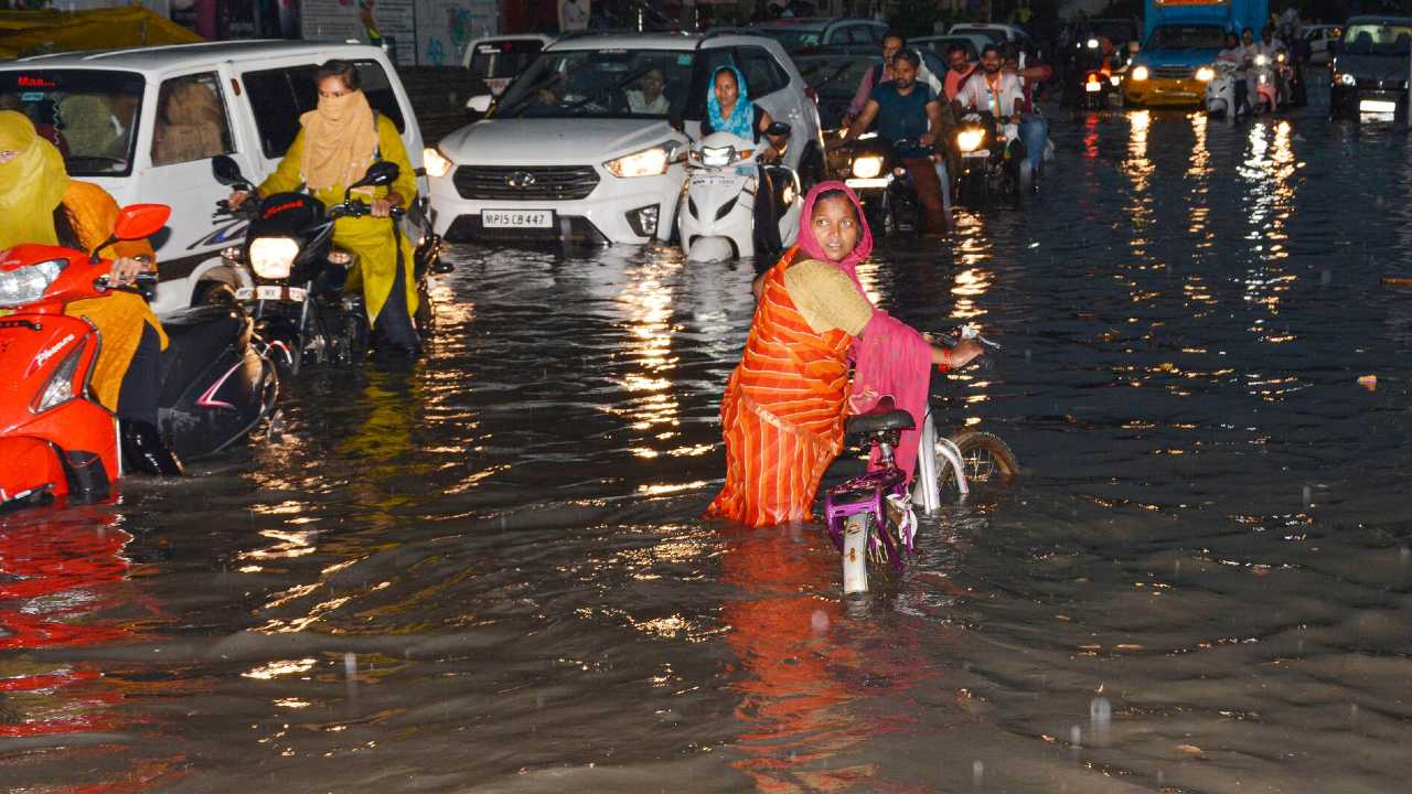 Les navetteurs pataugent dans une rue gorgée d'eau après la pluie, à Jabalpur, le mercredi 29 juin 2022. (Crédit : PTI)