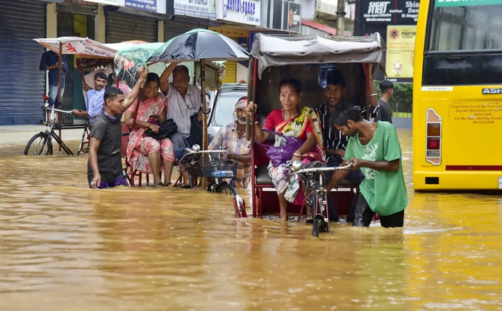 Guwahati: Rickshaw pullers wade through a flooded street after rains, in Guwahati on Tuesday, June 14, 2022. (Photo PTI) 