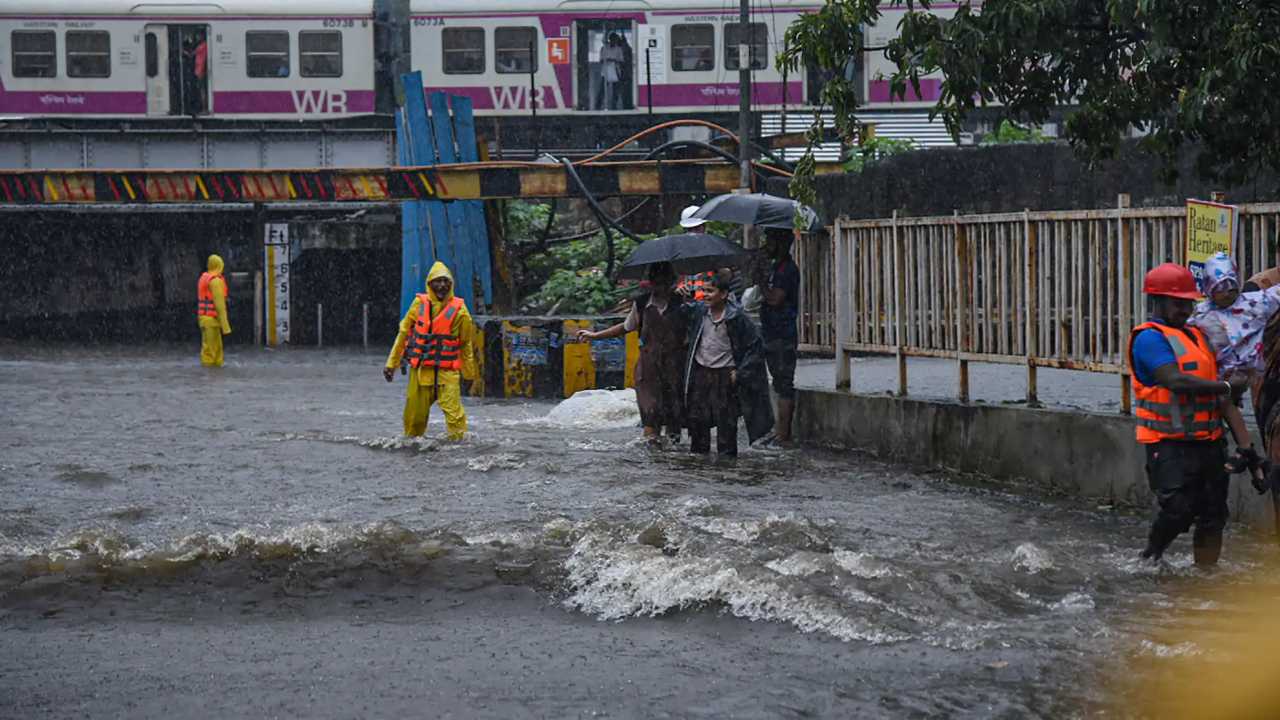 People wade through a waterlogged street amid monsoon rains, near the closed Andheri Subway in Mumbai, Tuesday, July 5, 2022. (Image: PTI)