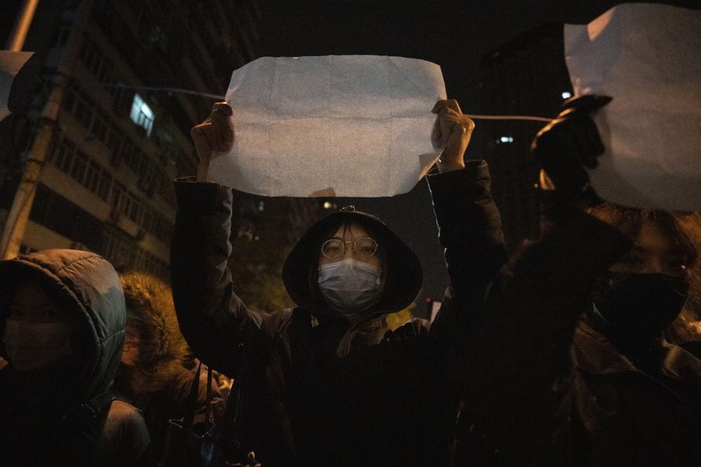 A protestor holds up a blank paper and chant slogans during a march in protest in Beijing, Sunday, Nov. 27, 2022.