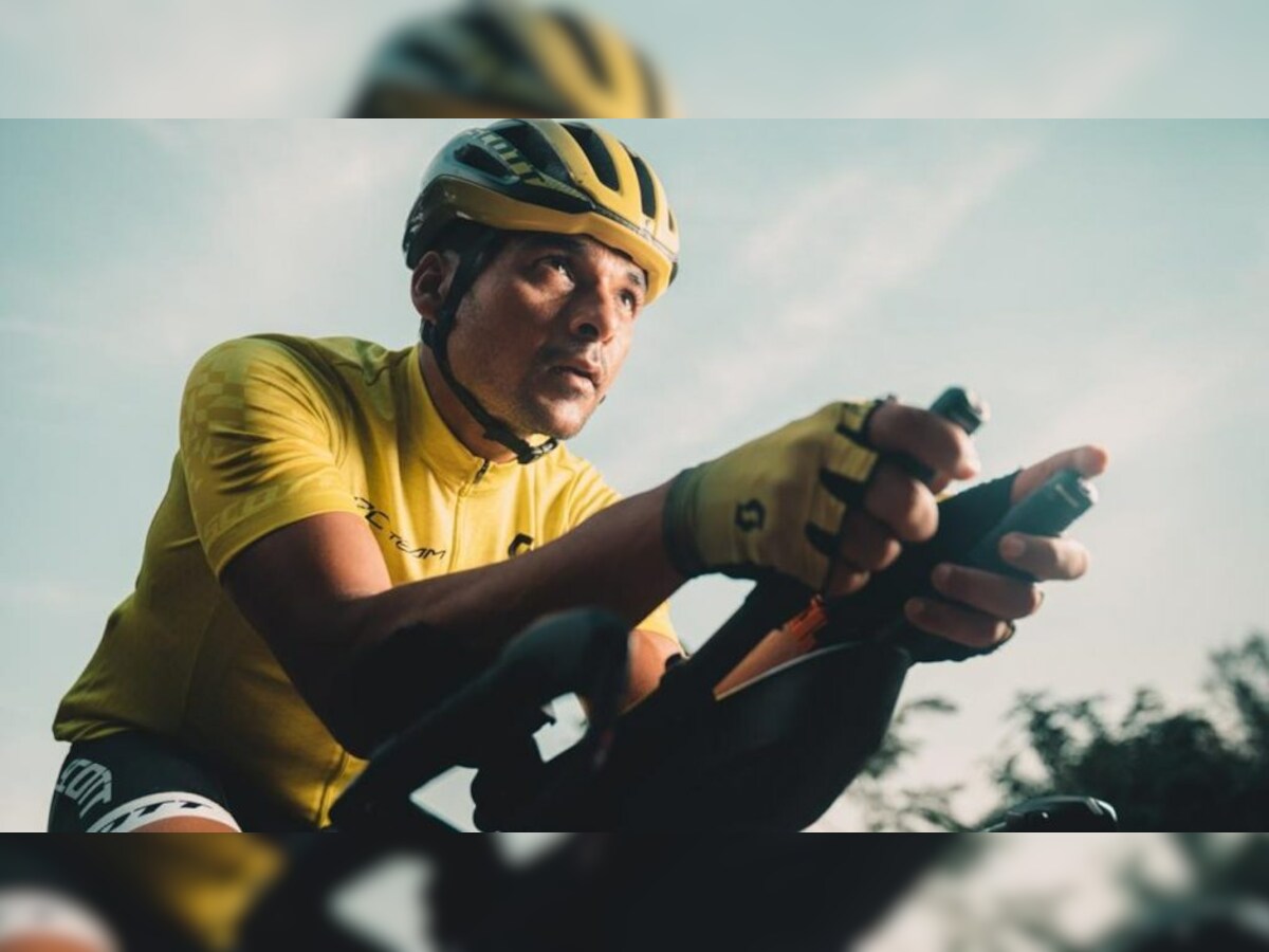 Focus on Asian man wearing a yellow cycling jersey, who's riding a